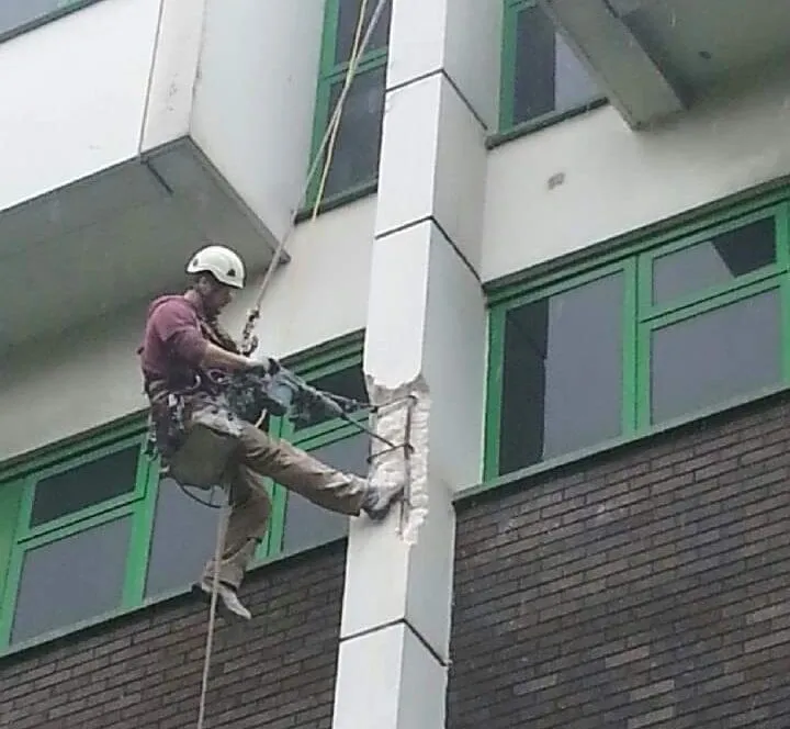 abseiling man repairing concrete